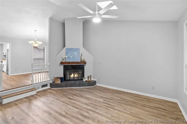 an empty room with wooden floor fireplace cabinet and windows