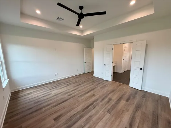 an empty room with wooden floor and a ceiling fan