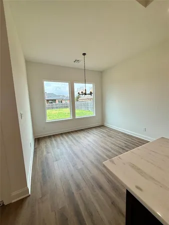 a view of a room with kitchen island stainless steel appliances wooden floor and window