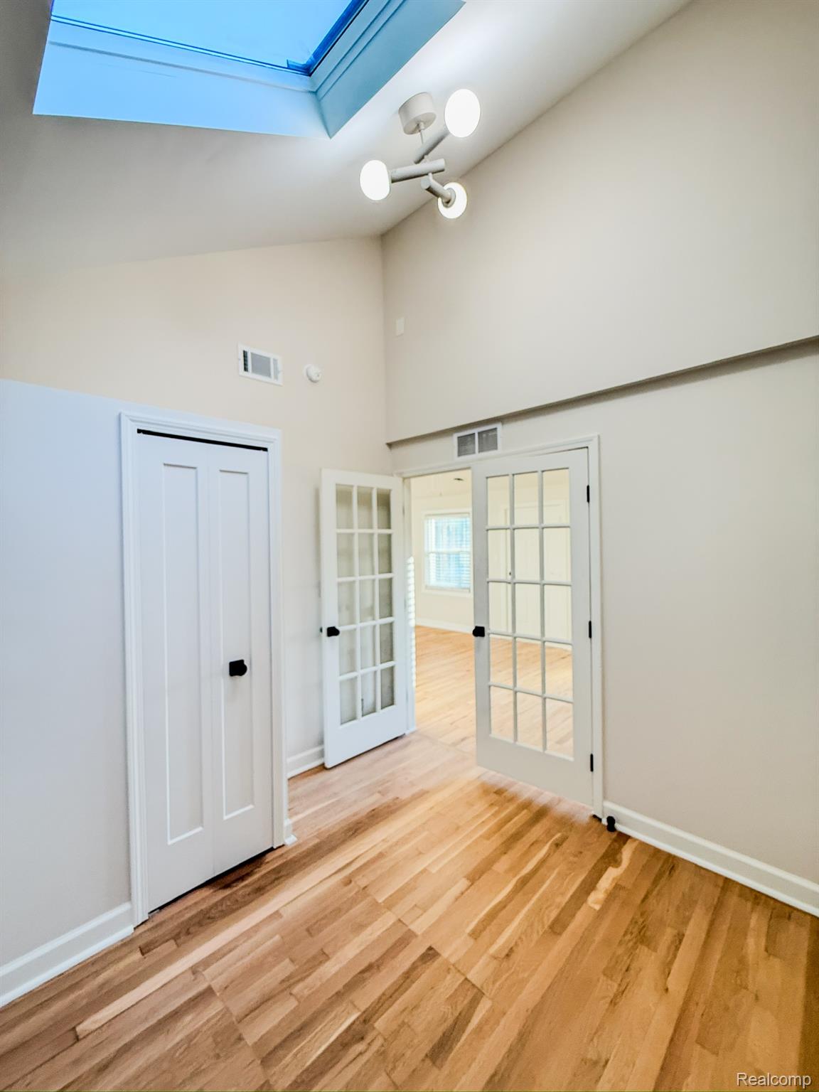 30052 Schoenherr Road Warren, MI 48088 - Photo 22 of 38 Vaulted ceiling with an overhead skylight, wood-finish flooring, and contemporary light fixture