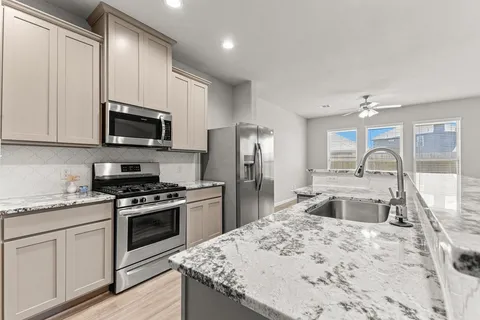 a kitchen with stainless steel appliances granite countertop a sink stove and refrigerator