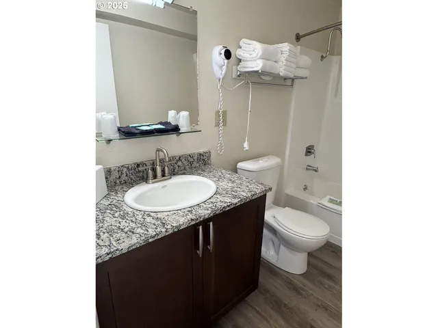 a bathroom with a granite countertop sink a toilet and a mirror