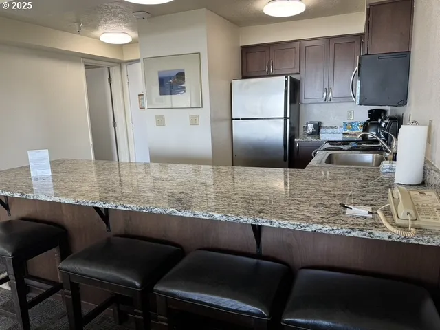 a kitchen with granite countertop cabinets a refrigerator and a sink