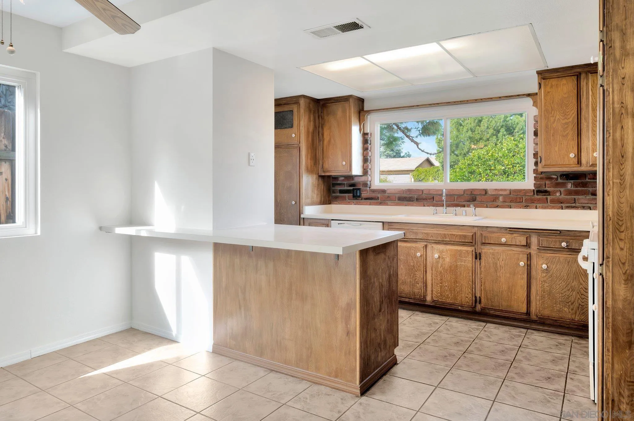 9183 Via De Amor Santee, CA 92071 - Photo 5 of 32 a kitchen with kitchen island granite countertop a sink window and cabinets
