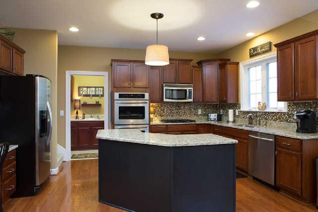 5524 Rathkeale Lane Franklin, TN 37067 - Photo 10 of 20 Kitchen features massive island with granite, upgraded cabinetry, built-in desk, new light fixtures & hardwood flooring. Notice the casement windows with views of huge backyard. Large Mudroom/Laundry Room is located off of kitchen.