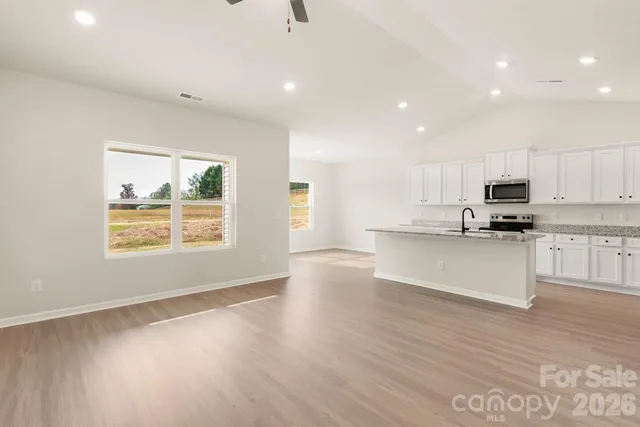 a view of kitchen with granite countertop stainless steel appliances stove sink and cabinets