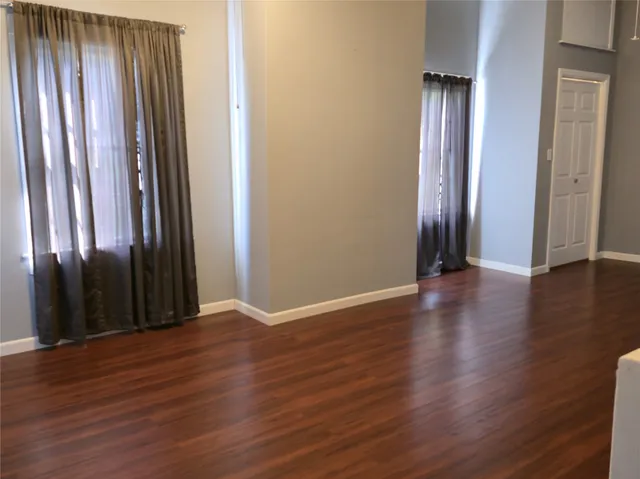 an empty room with wooden floor and a mirror