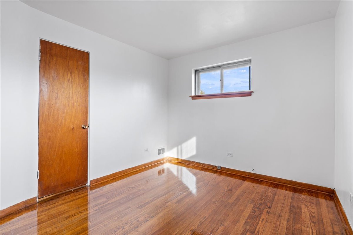 852 East 88th Place Chicago, IL 60619 - Photo 17 of 28 an empty room with wooden floor and a window