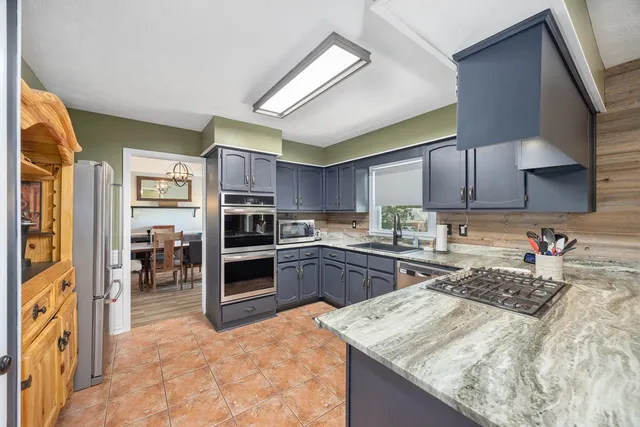 a kitchen with stainless steel appliances granite countertop a stove refrigerator and a sink