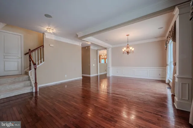 a view of a livingroom with wooden floor staircase and a kitchen space