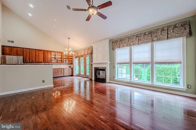 a living room with stainless steel appliances wooden floors and a fireplace