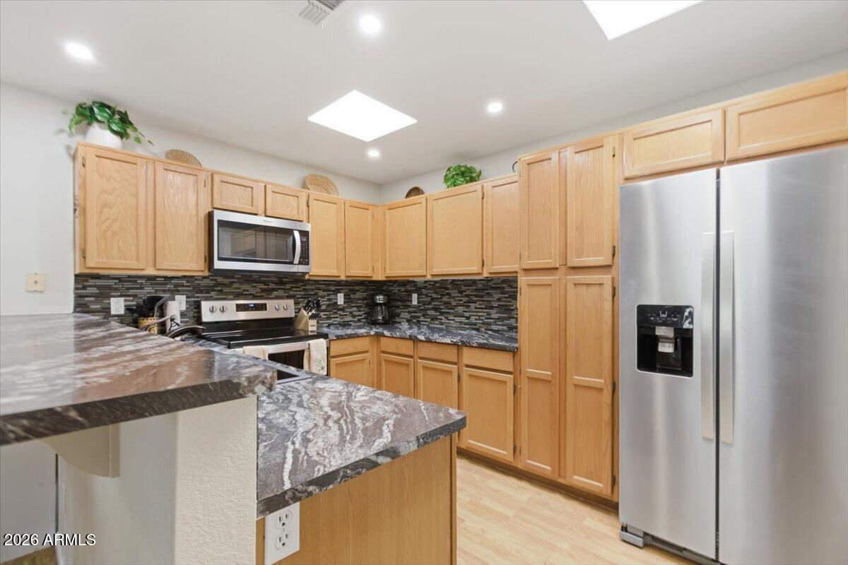 14300 West Bell Road, Unit 211 Surprise, AZ 85374 - Photo 10 of 42 a kitchen with kitchen island granite countertop white cabinets refrigerator and microwave