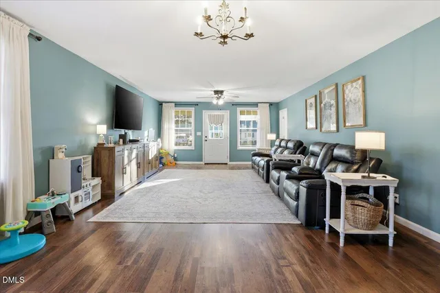a living room with furniture a flat screen tv and a floor to ceiling window