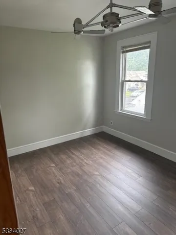 an empty room with a ceiling fan and window