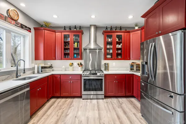 a kitchen with stainless steel appliances granite countertop a refrigerator a sink dishwasher a stove and a dining table with wooden floor