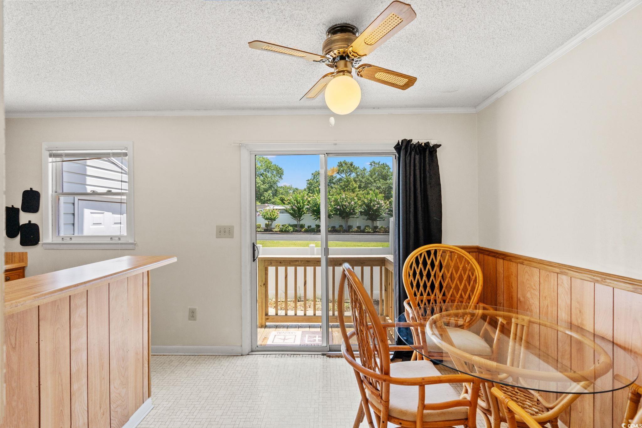 4115 Little River Road, Unit 10E Myrtle Beach, SC 29577 - Photo 7 of 23 Dining space with a textured ceiling, ceiling fan, crown molding, and wood walls