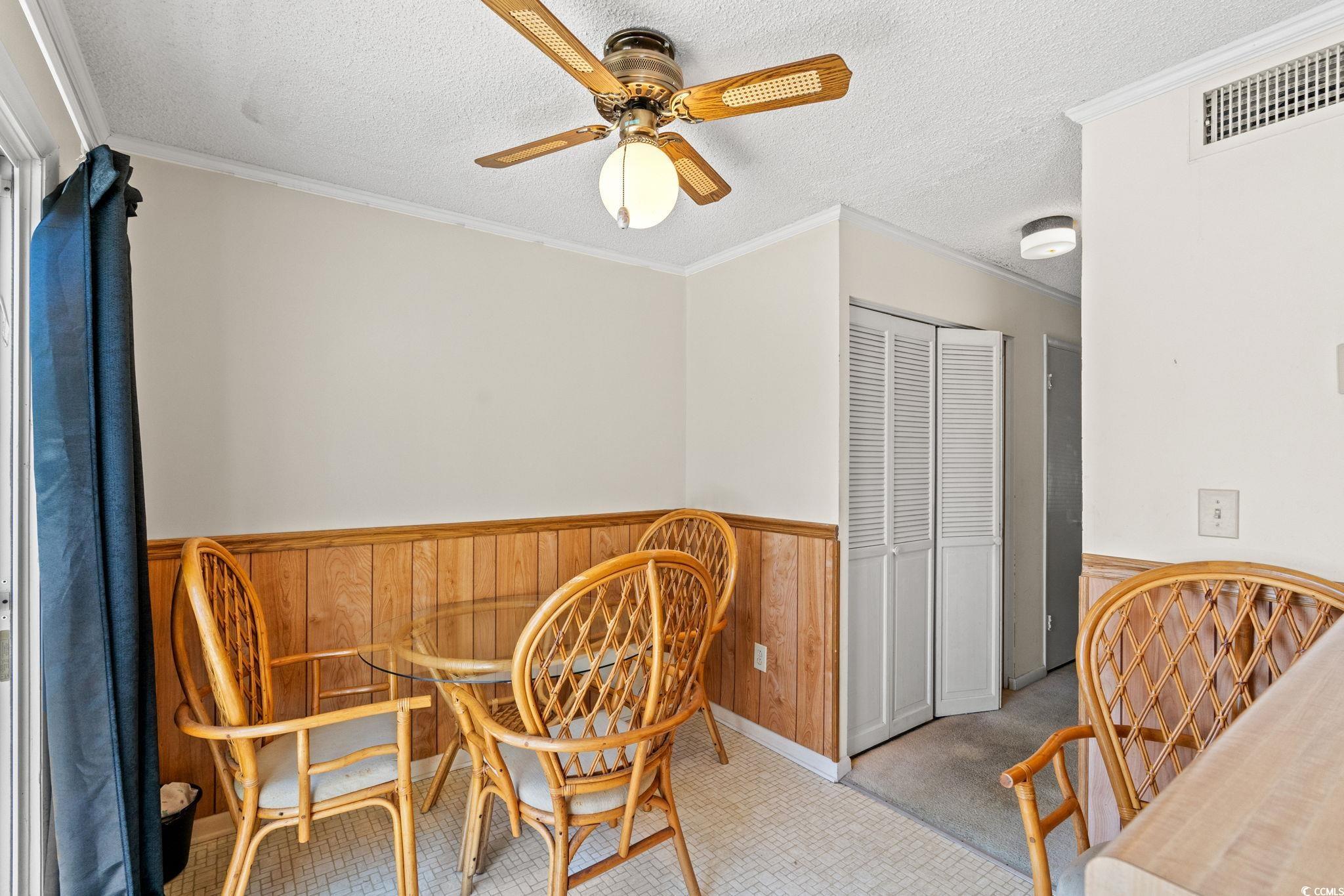 4115 Little River Road, Unit 10E Myrtle Beach, SC 29577 - Photo 8 of 23 Living area with a wainscoted wall, ceiling fan, a textured ceiling, and ornamental molding