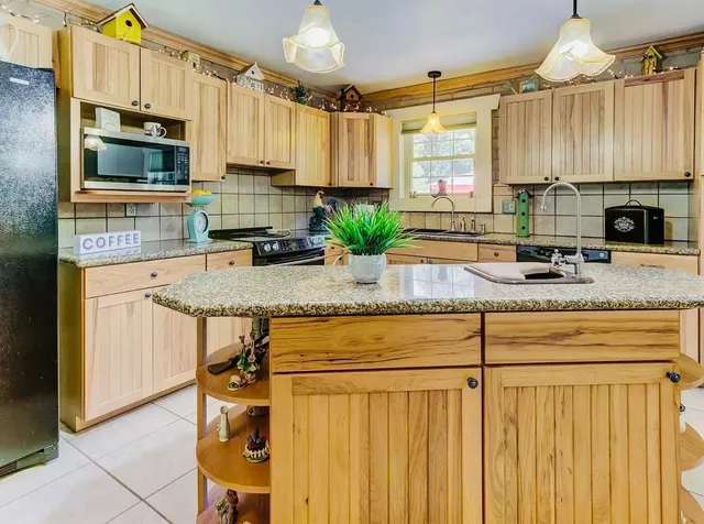 a kitchen with granite countertop a stove a sink and a microwave