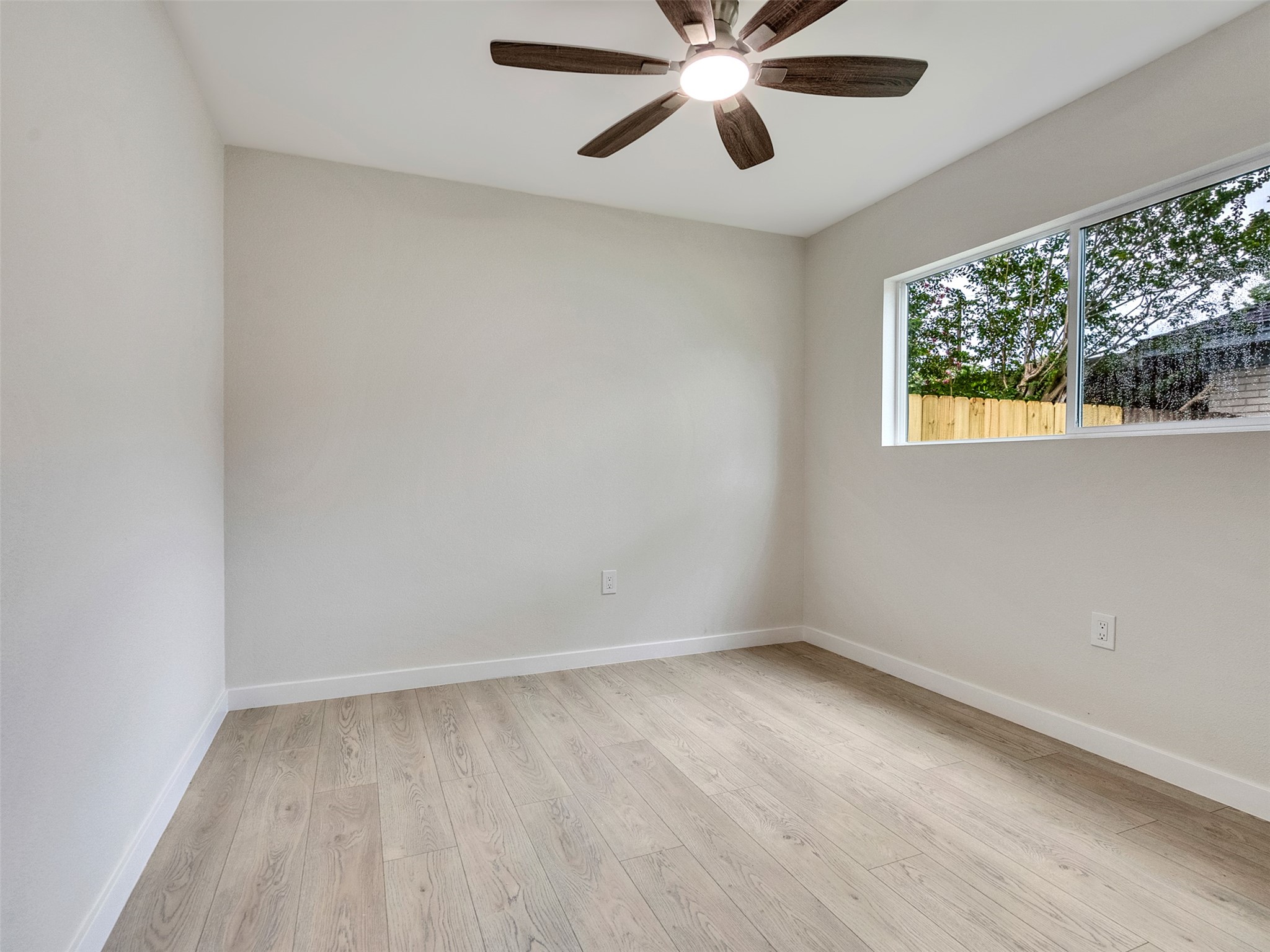 10315 Winding Trail Road La Porte, TX 77571 - Photo 17 of 24 Experience tranquility in Bedroom #3, featuring sleek luxury vinyl plank flooring, a chic ceiling fan, and abundant natural light from a large window overlooking lush greenery.