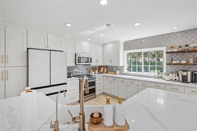 a kitchen with a sink a stove a refrigerator and white cabinets