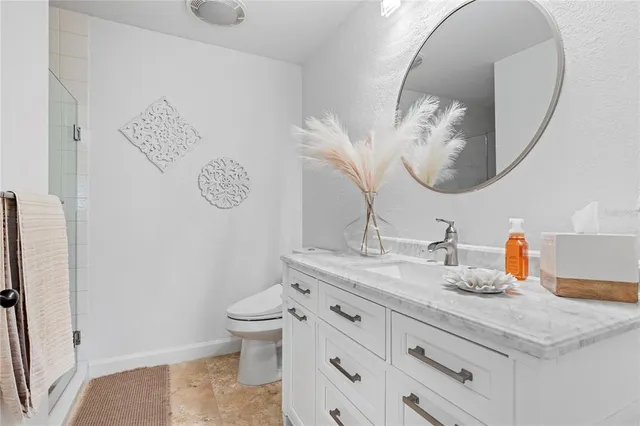 a bathroom with a granite countertop sink mirror vanity and toilet