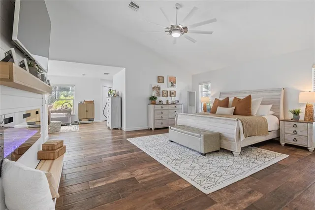 a spacious bedroom with a bed and wooden floor