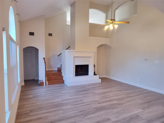 an empty room with wooden floor fireplace and staircase