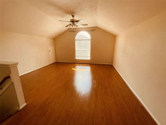 an empty room with wooden floor fan and windows