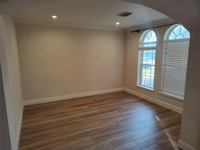 an empty room with wooden floor and windows