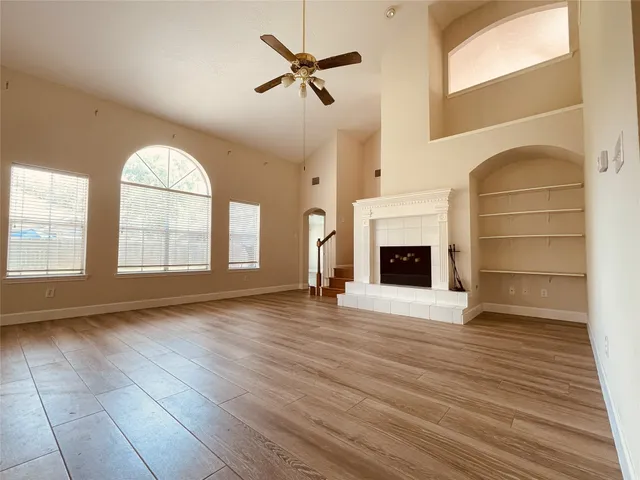 an empty room with wooden floor fireplace and windows