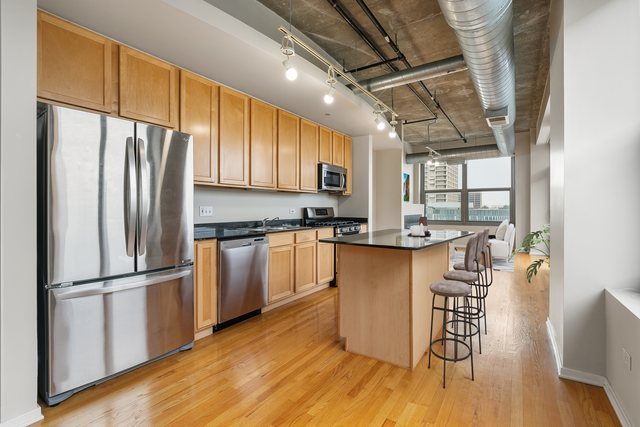 933 West Van Buren Street, Unit 516 Chicago, IL 60607 - Photo 6 of 29 a kitchen with granite countertop stainless steel appliances a refrigerator a stove top oven and a dining table