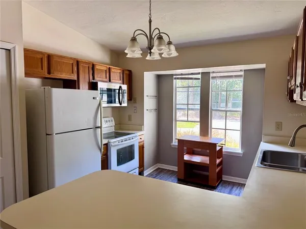 a kitchen with stainless steel appliances granite countertop a refrigerator a stove a sink dishwasher a dining table and chairs with wooden floor