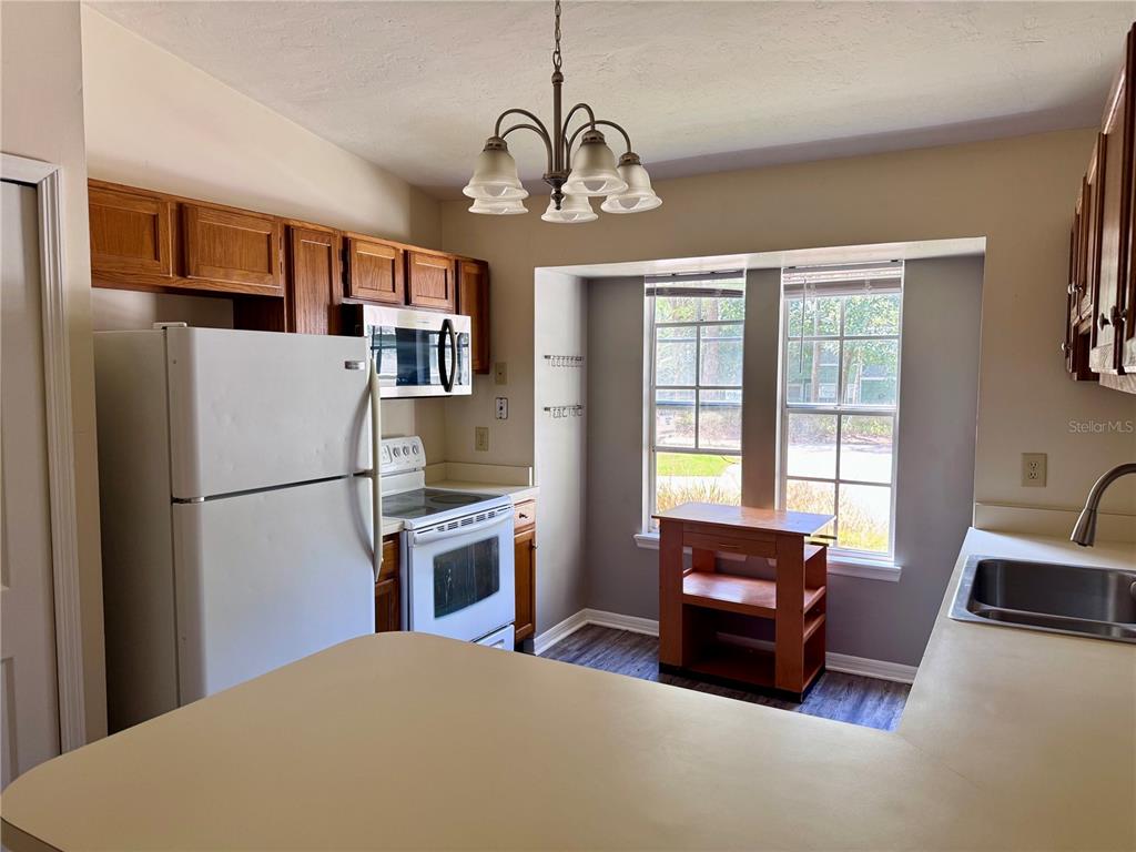 329 Northwest 48th Boulevard Gainesville, FL 32607 - Photo 4 of 7 a kitchen with stainless steel appliances granite countertop a refrigerator a stove a sink dishwasher a dining table and chairs with wooden floor