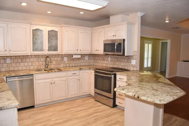 a kitchen with stainless steel appliances kitchen island granite countertop a sink stove and microwave