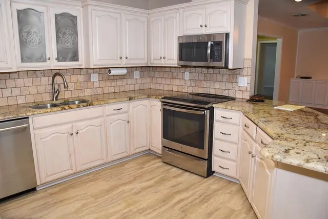 a kitchen with granite countertop cabinets stainless steel appliances and wooden floor