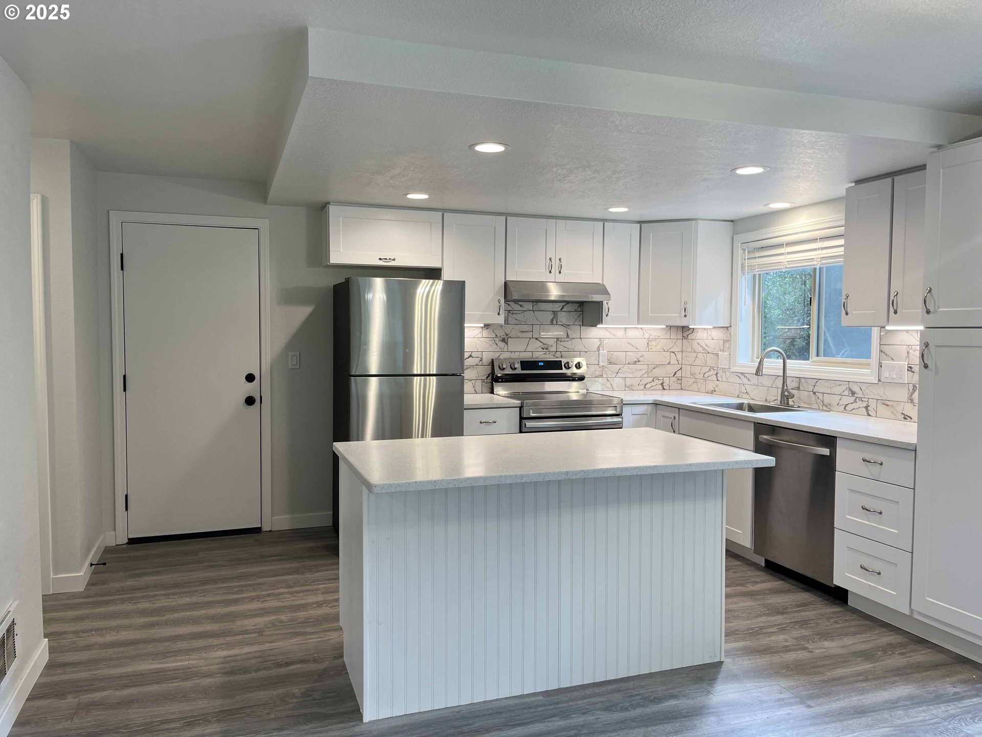 2040 11th Street Florence, OR 97439 - Photo 11 of 43 a kitchen with kitchen island white cabinets and stainless steel appliances