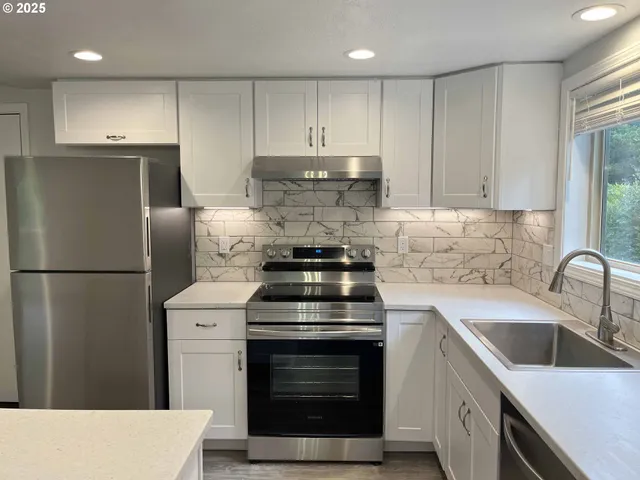 a kitchen with granite countertop white cabinets sink and white appliances