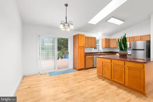 a view of a kitchen with kitchen island a counter top space a sink stainless steel appliances and cabinets