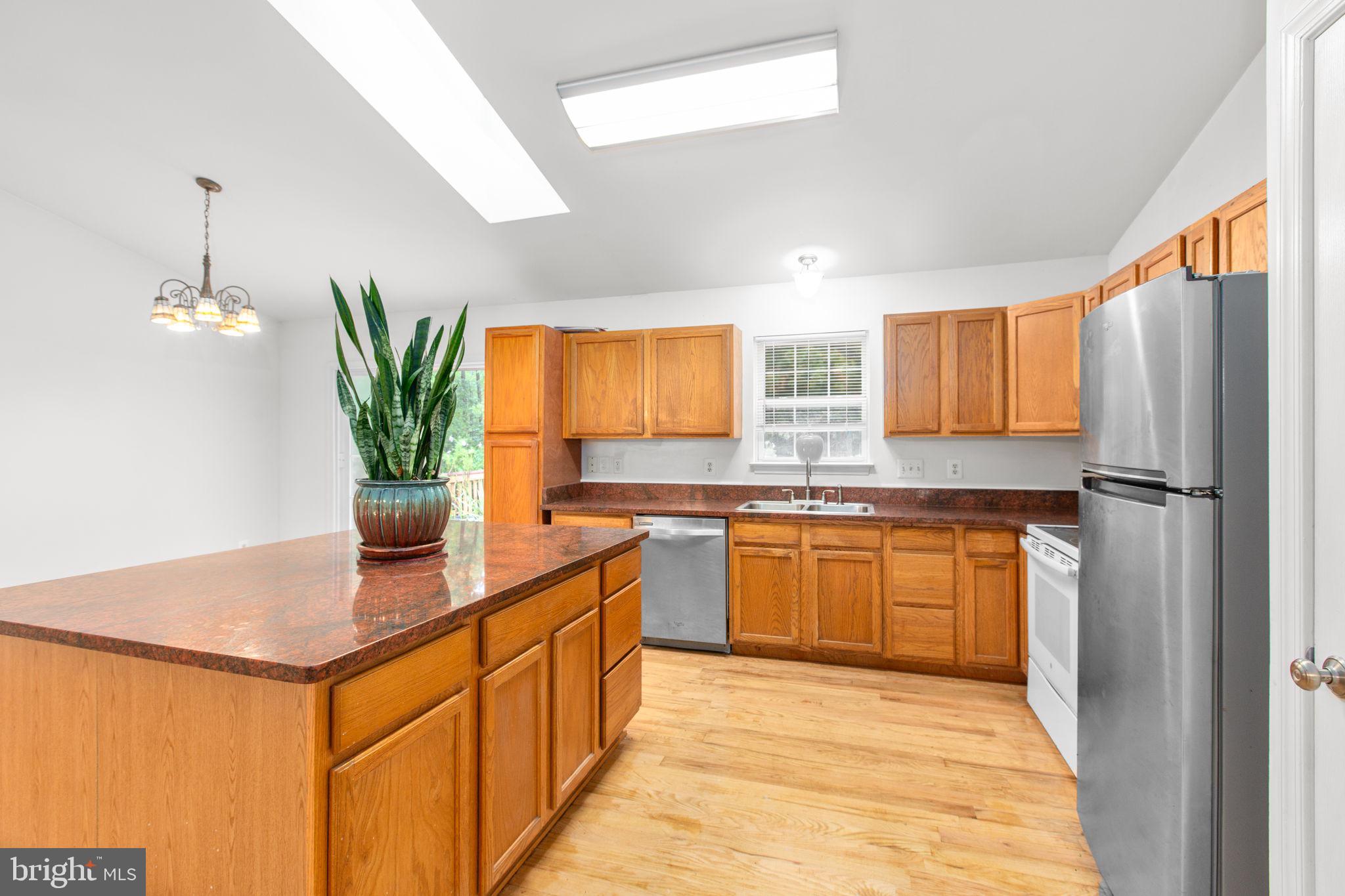 53 Bloomington Lane Stafford, VA 22554 - Photo 8 of 60 a kitchen with stainless steel appliances granite countertop a refrigerator a sink dishwasher a stove a dining table and chairs with wooden floor