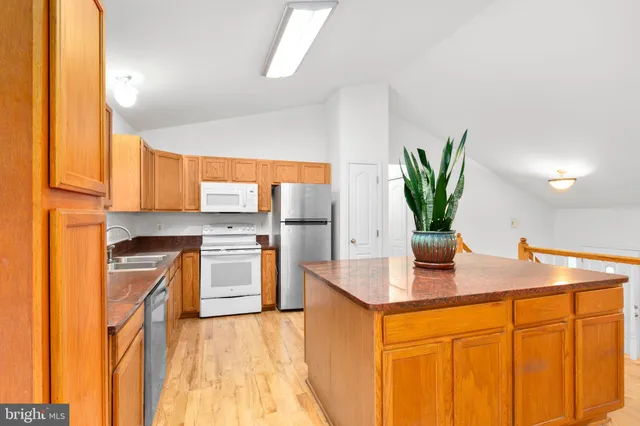 a kitchen with stainless steel appliances granite countertop a sink a faucet cabinets and a dining table