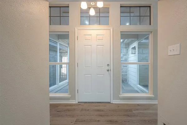 an empty room with windows fireplace and wooden floor