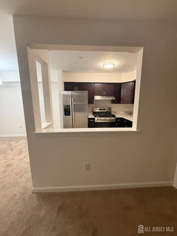 a living room with stainless steel appliances a wooden floor and a sink