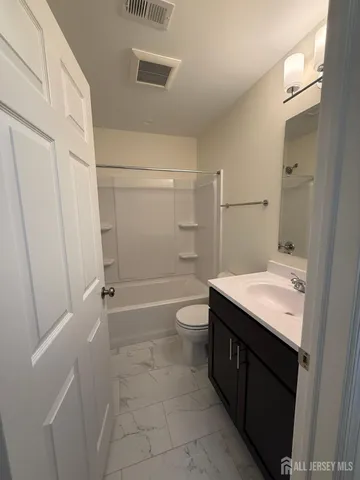 a bathroom with a granite countertop sink a toilet and shower