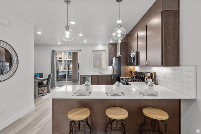 1122 South 1790th West, Unit 1 St. George, UT 84770 - Photo 6 of 37 Modern kitchen featuring a breakfast bar with seating, white countertops, dark wood-finish cabinetry, and a subway tile backsplash
