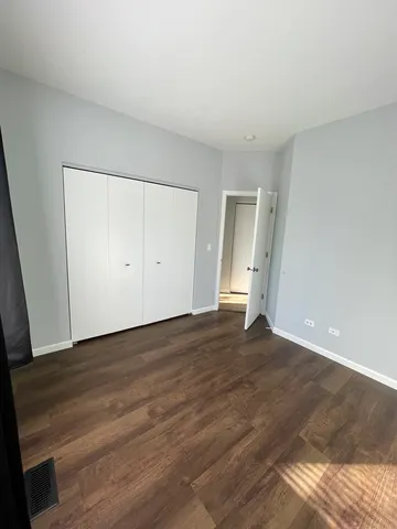 a view of an empty room with wooden floor and closet