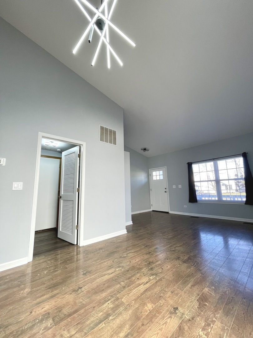 16623 Natoma Drive, Unit 16623 Lockport, IL 60441 - Photo 2 of 27 an empty room with wooden floor chandelier and windows