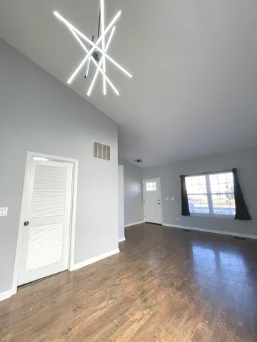 a view of an empty room with window and wooden floor
