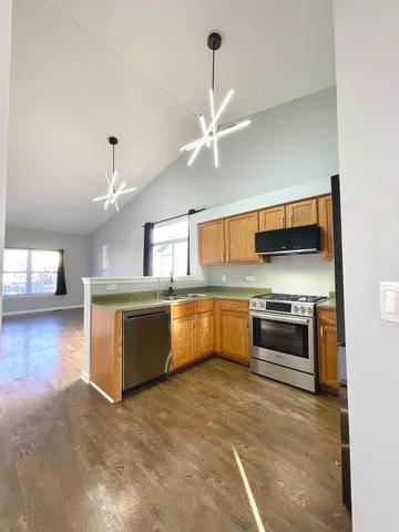 a kitchen with stainless steel appliances kitchen island granite countertop a stove and a view of living room