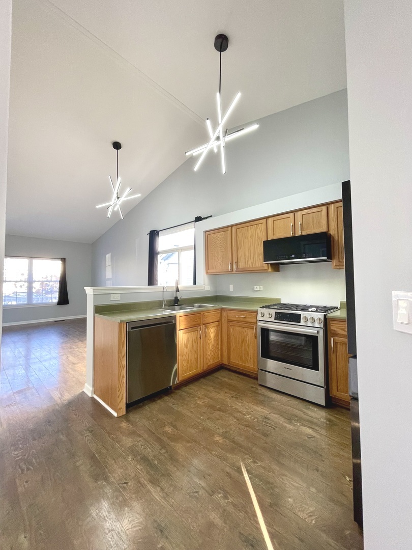 16623 Natoma Drive, Unit 16623 Lockport, IL 60441 - Photo 4 of 27 a kitchen with stainless steel appliances kitchen island granite countertop a stove and a view of living room