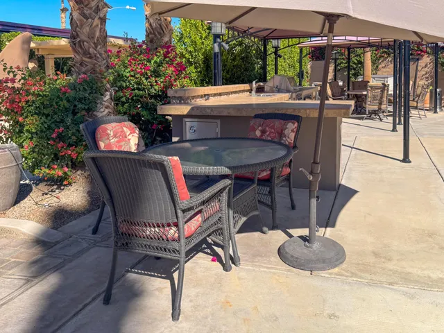 a view of a patio with a dining table and chairs under an umbrella with a fire pit